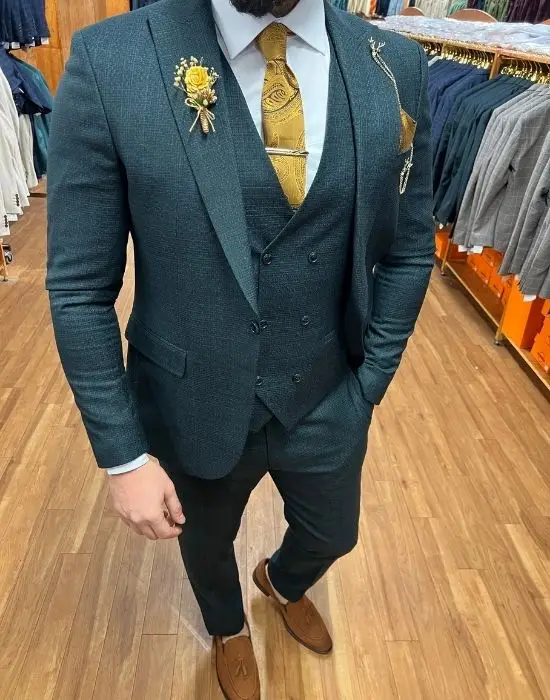 Homme en costume trois pièces vert avec cravate dorée