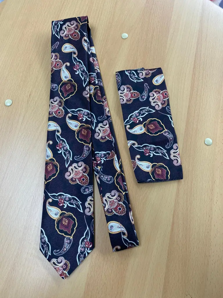 Cravate et pochette motif paisley sur table en bois