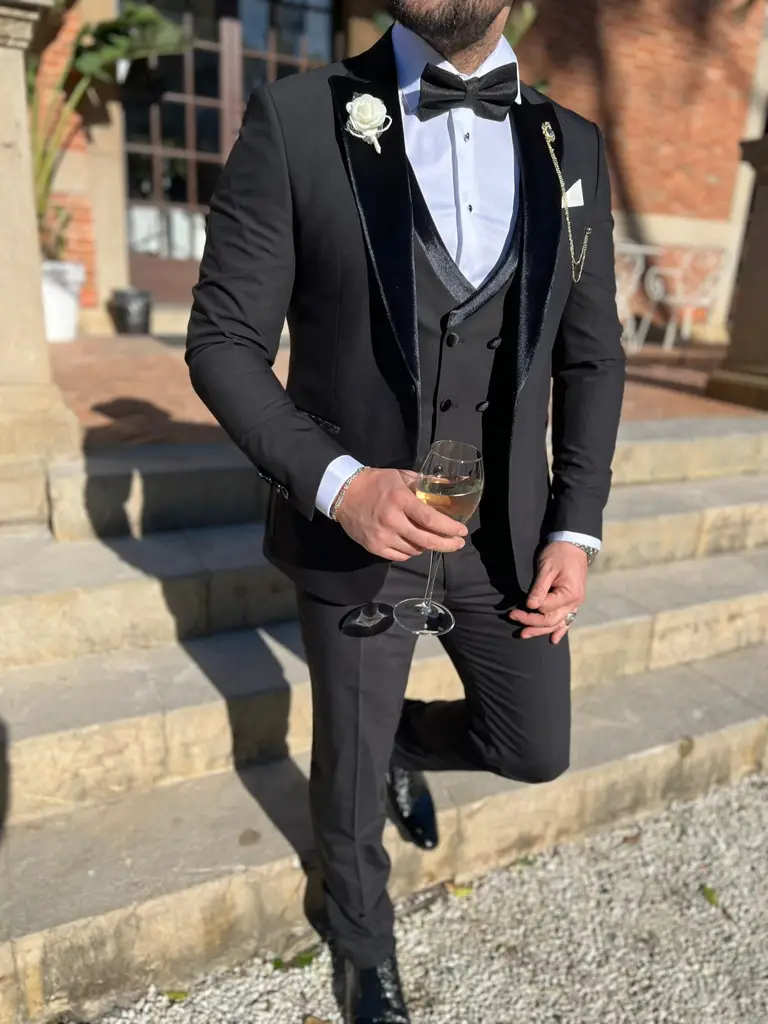 Homme en smoking noir avec verre de vin blanc