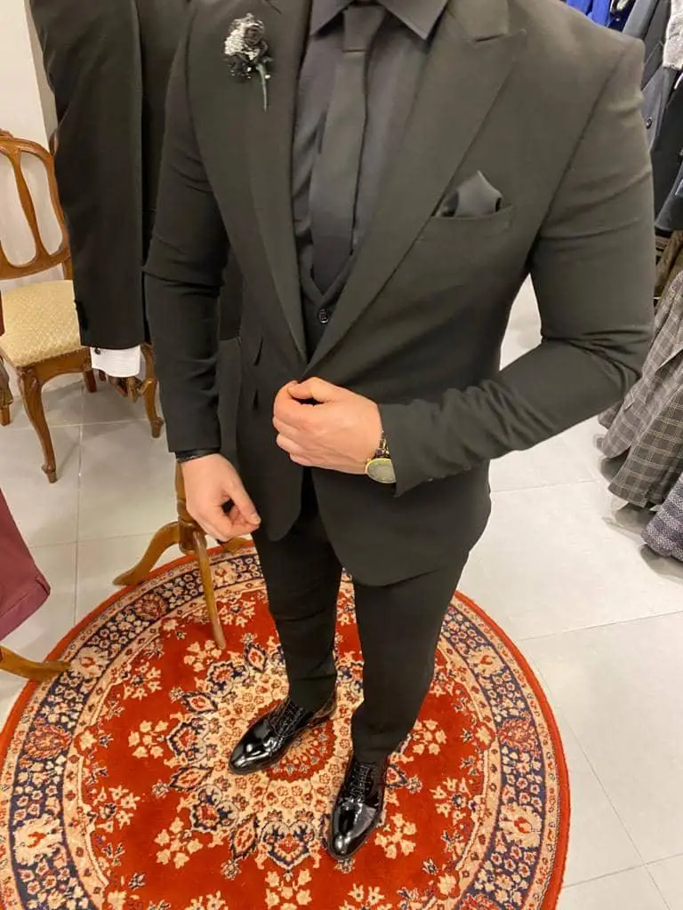 Man in stijlvol zwart pak met bloemcorsage op rode tapijt