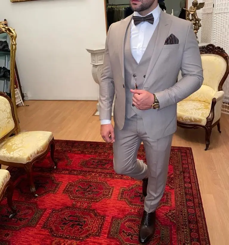 Homme en costume beige élégant avec nœud papillon.